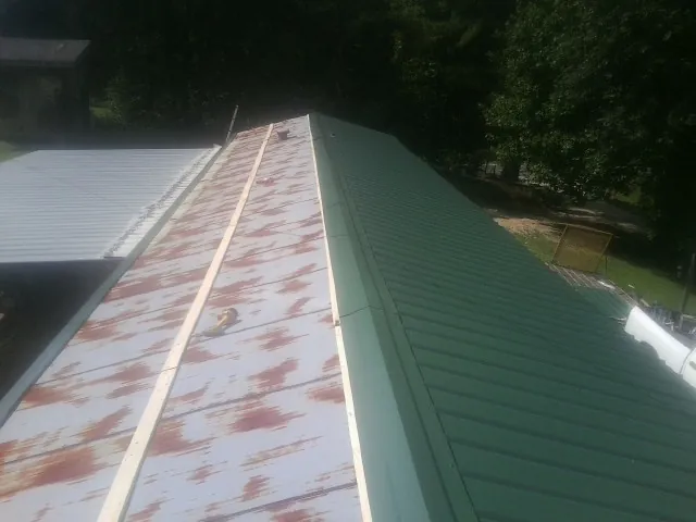 Old rusted panels beside newly installed green metal roofing — Wind Damage Roof Repair by Roofing Brothers in Red Oak